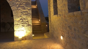 Un antico edificio in pietra con una scala che conduce a un piano superiore.