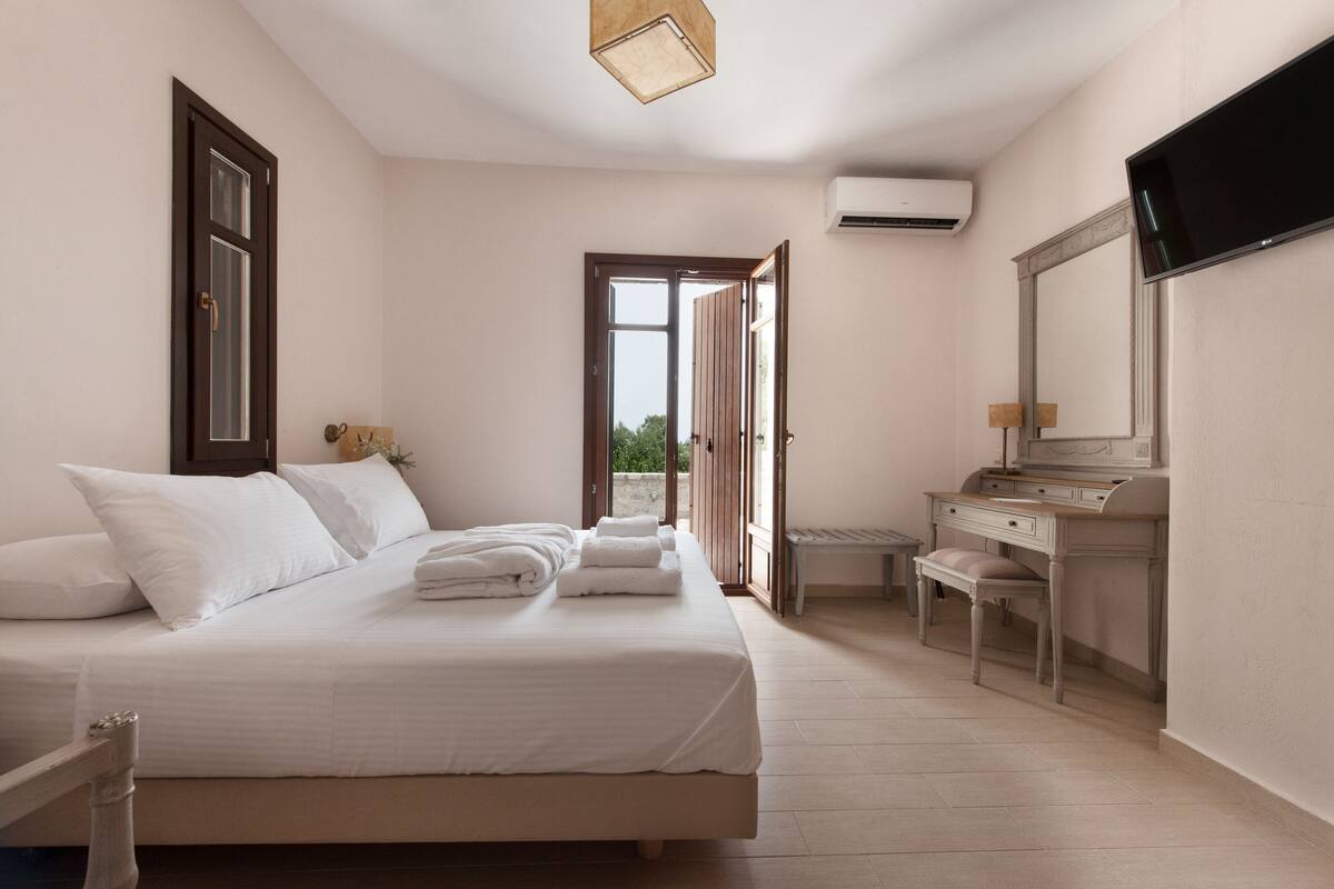 Une chambre d’hôtel équipée d’un lit, d’un bureau, d’une chaise, d’une télévision et d’un appareil de climatisation.