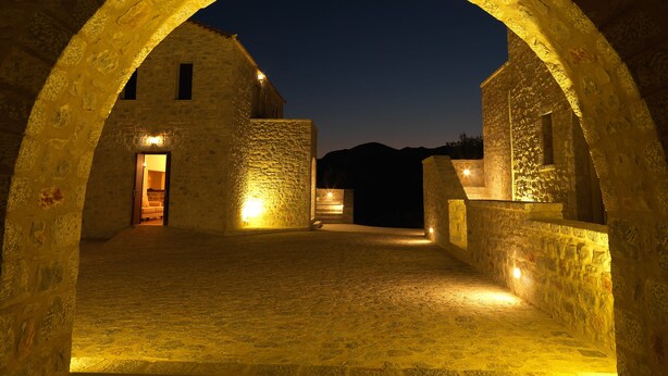 Una struttura ad arco in pietra con pavimento in pietra, illuminata da luci calde.