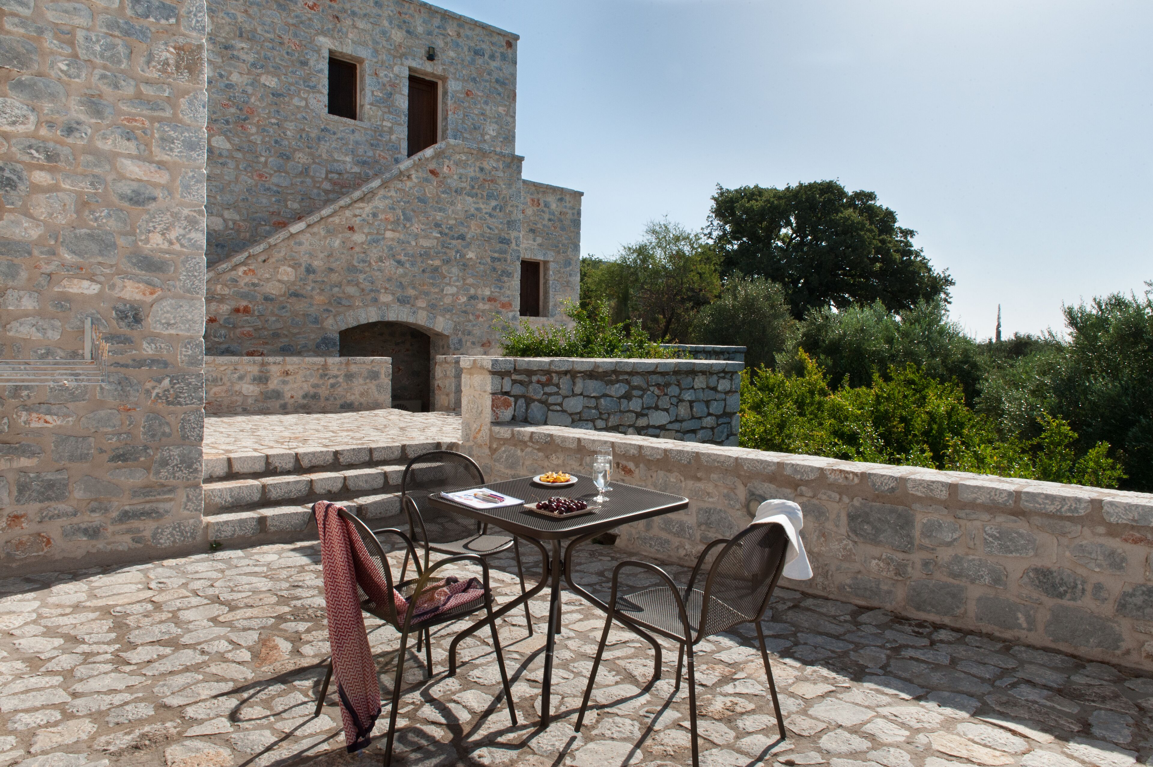 An outdoor patio with stone flooring, a table with chairs, and a stone wall.