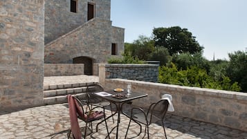 An outdoor patio with stone flooring, a table with chairs, and a stone wall.