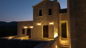 Un edificio in pietra con diverse finestre e porte, illuminato da luci esterne.
