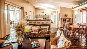 A spacious living room with a brown leather sofa, a coffee table, and a dining area with wooden chairs and a table. - Ngoye Lodge (eMthunzini)