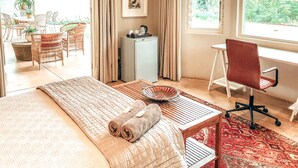 A well-lit room with a bed, a desk, a chair, and a view of greenery outside. - Ngoye Lodge (eMthunzini)