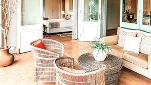 A spacious living area with a sofa, wicker chairs, a round coffee table, and a potted plant. - Ngoye Lodge (eMthunzini)