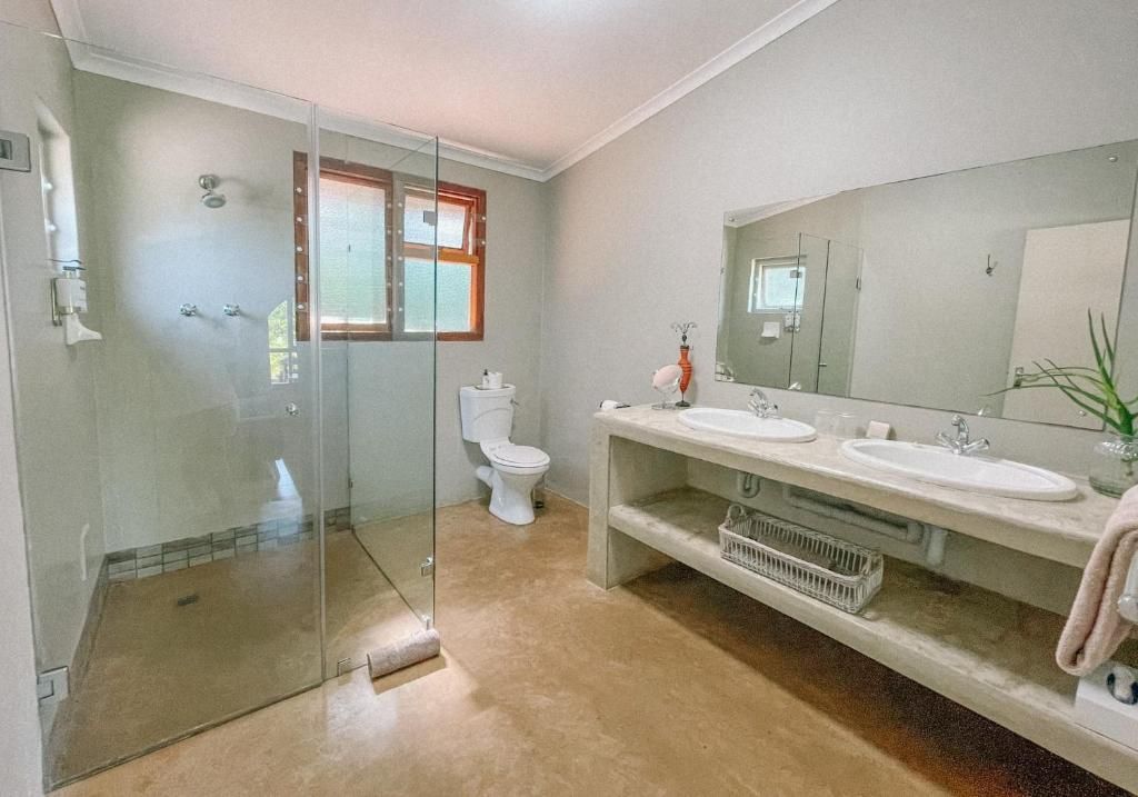 Un baño con cabina de ducha de vidrio, inodoro y tocador doble con espejo.