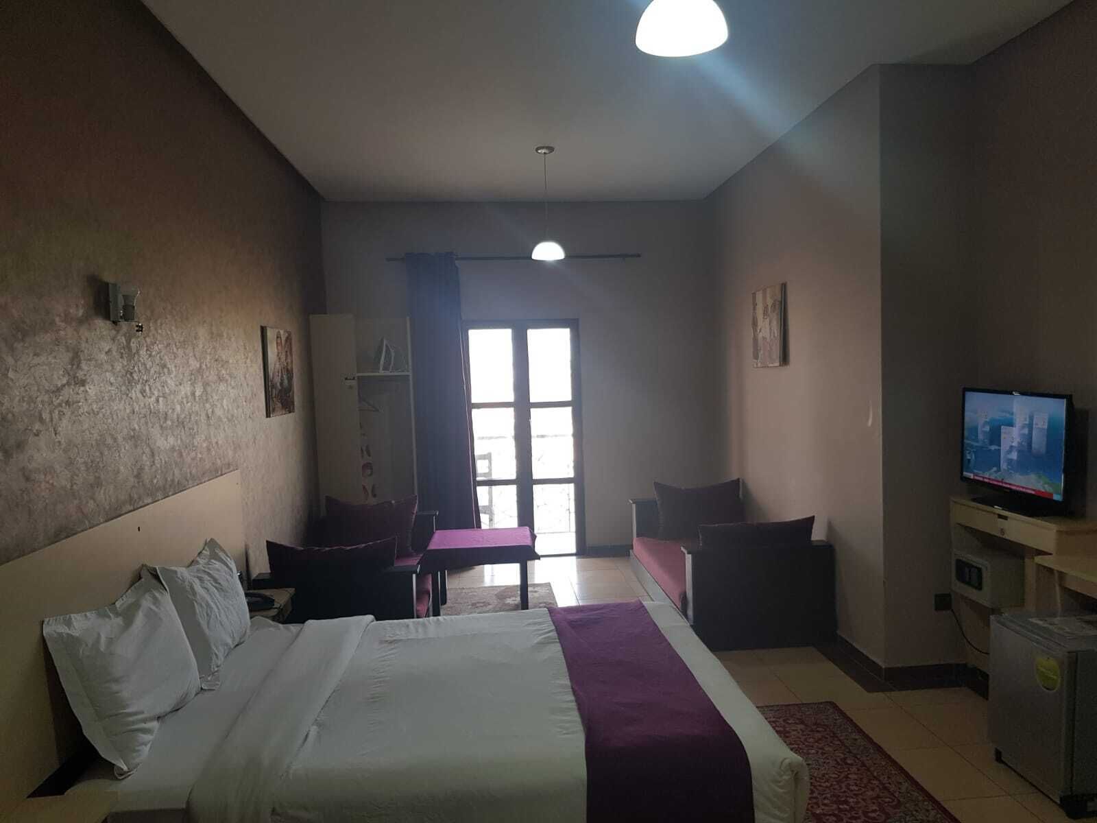 A hotel room with a bed, a desk, a chair, a television, and a wardrobe.