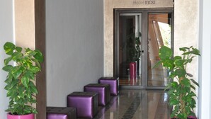 Un vestíbulo de hotel con un cartel de 'Bienvenue', un mostrador de recepción y una escalera que sube a los pisos superiores.