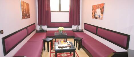A room with a sofa set, a small table with a vase and candles, and artwork on the walls.