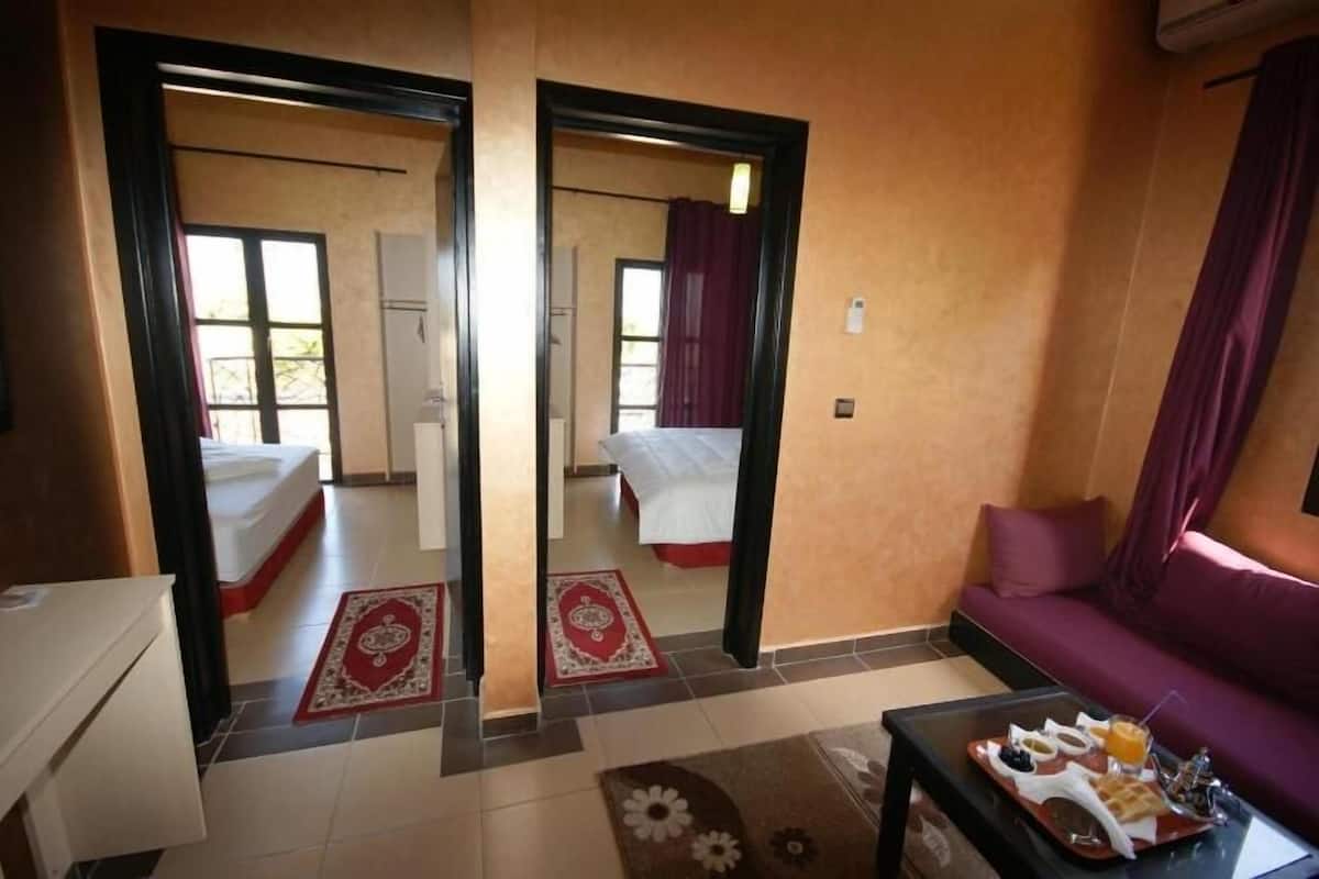 A hotel room with a sofa, a dining table with breakfast, and a mirror reflecting the room.