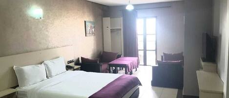Una habitación de hotel con una cama grande, un escritorio, una silla y un televisor.