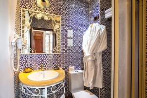 Un baño con un lavabo redondo, un inodoro y un espejo con un marco decorativo.