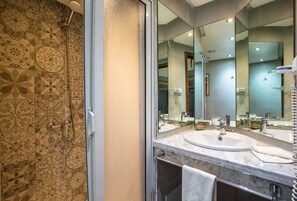 Un baño con baldosas estampadas, un espejo grande, un lavamanos y una ducha.