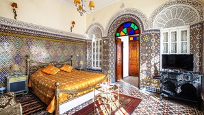 Una habitación con una cama grande, televisión y elaborados trabajos en azulejos en las paredes y el suelo.