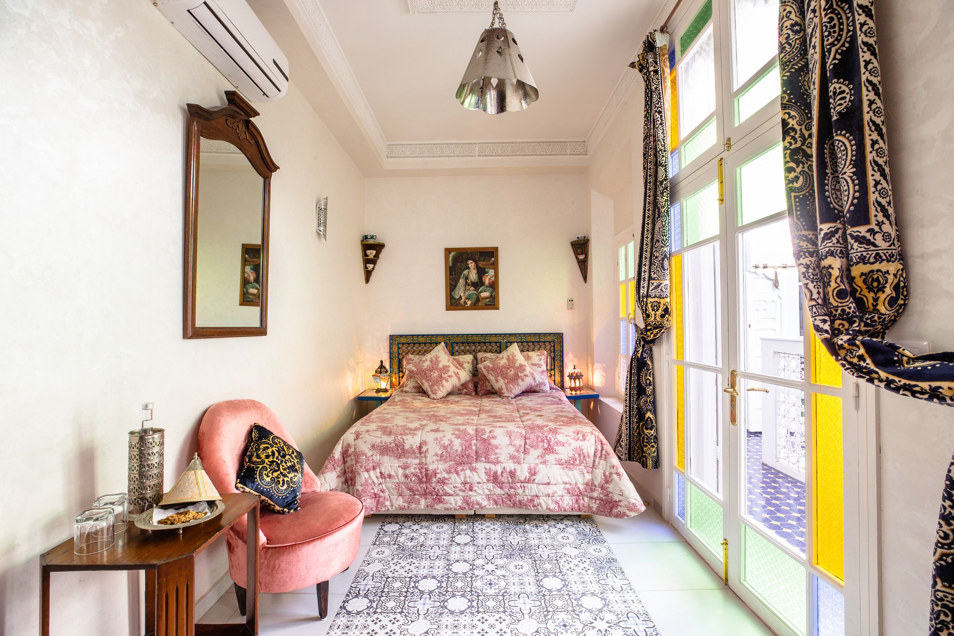 A bedroom with a bed, a chair, a table, and a window with curtains.