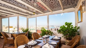 Un comedor con mobiliario de mimbre, vistas a la ciudad y un techo con diseños elaborados.