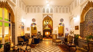 Un interior tradicional con arcos ornamentados, una chimenea central y una variedad de arreglos de asientos.