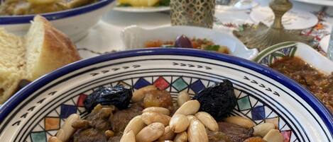 A dining table with a variety of dishes, including a bowl of couscous with almonds and dried fruits, and other plates with different foods.