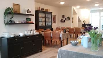 Un'area pranzo con un armadietto nero, sedie in legno e un tavolo con tovaglia grigia.