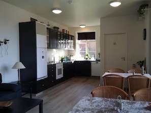 A modern kitchen with black cabinets, a dining table with four chairs, and a window with a view of the outside.
