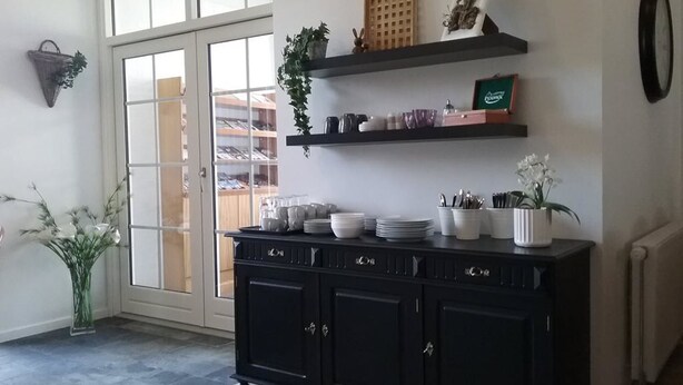 A modern kitchen with a black cabinet, white tiles, and a large window. - Hals Hotel (Hals)