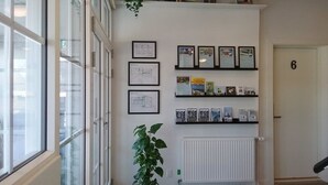 A hallway with a radiator, a potted plant, and framed certificates on the wall. - Hals Hotel (Hals)