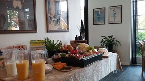 A breakfast buffet with various food items and drinks, a painting, and a window with a view of greenery. - Hals Hotel (Hals)