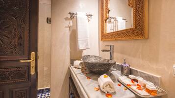 A bathroom with a marble countertop, a large ornate mirror, and a decorative door.