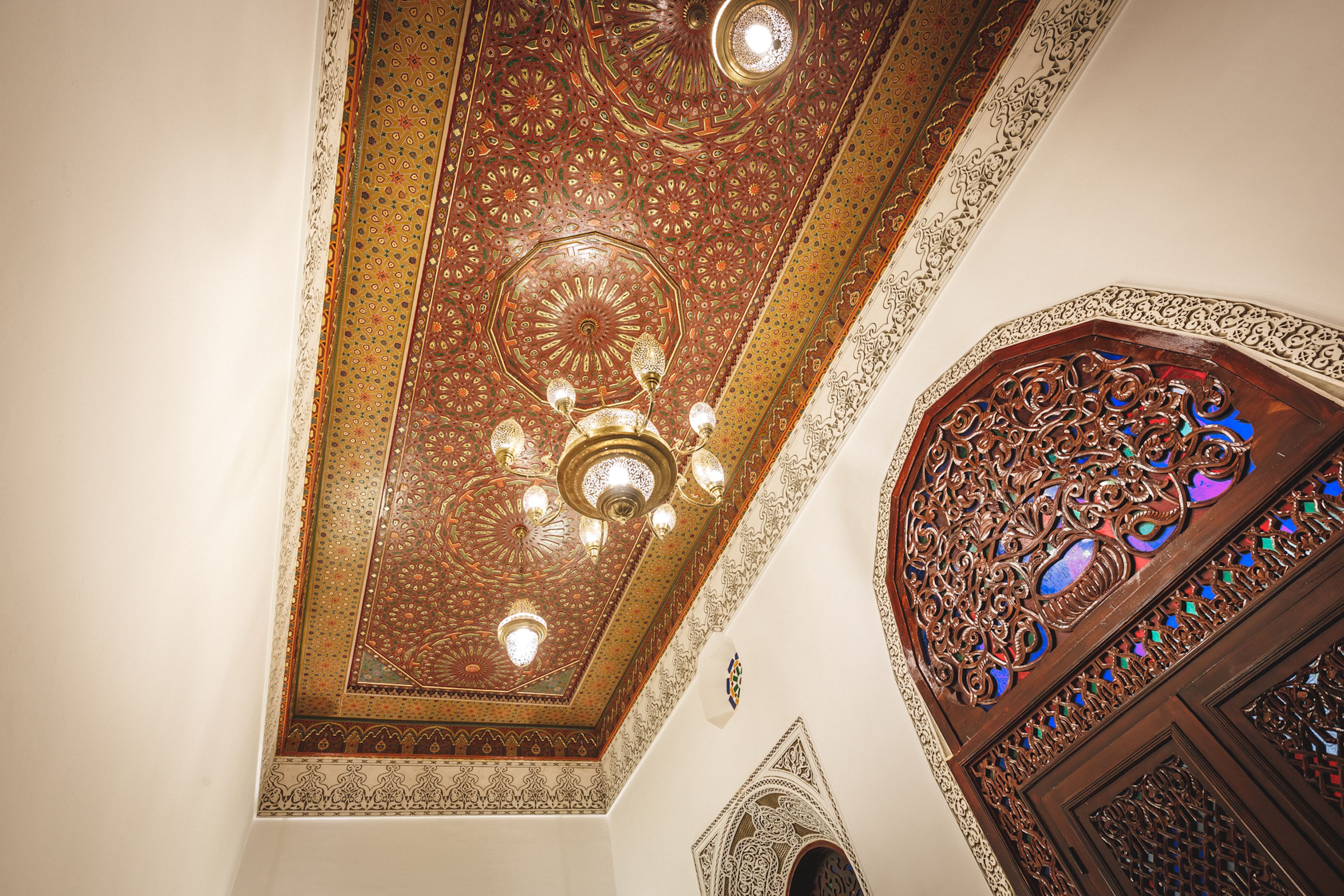A ceiling with intricate geometric patterns and a chandelier.