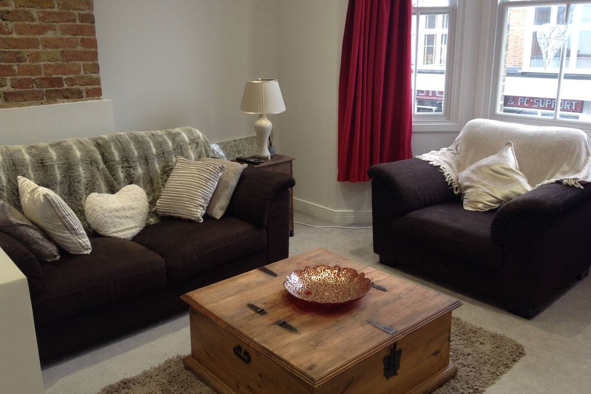A living room with two dark sofas, a wooden coffee table, and a lamp.