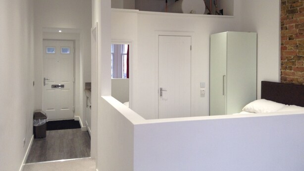 A modern bedroom with a loft area, a large wardrobe, and a visible water heater on the ceiling. - Central Windsor Apartments (Windsor)