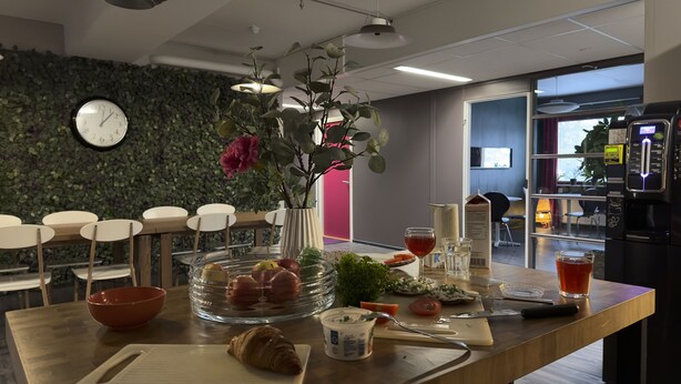 Una cocina moderna con encimera de madera, un florero con flores, un reloj y un refrigerador.