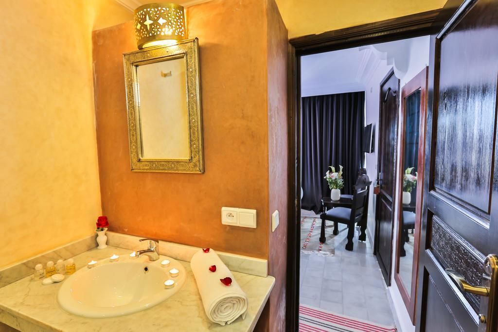 A bathroom with a marble sink, a mirror, and a decorative lamp.