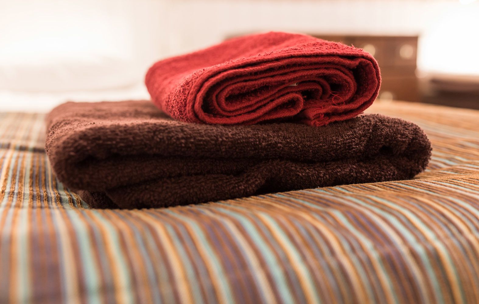 A neatly folded red towel on a striped pillow.