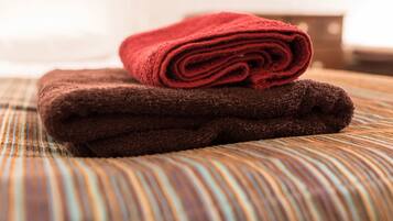 A neatly folded red towel on a striped pillow.