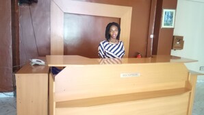 A reception desk with a "RECEPTION" sign, a telephone, and a framed picture on the wall. - Eminence Hotel (Kigali)