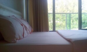 A hotel room with a bed, a window with curtains, and a view of greenery outside. - Eminence Hotel (Kigali)