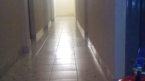 A corridor with tiled flooring and a red fire extinguisher on the right. - Eminence Hotel (Kigali)