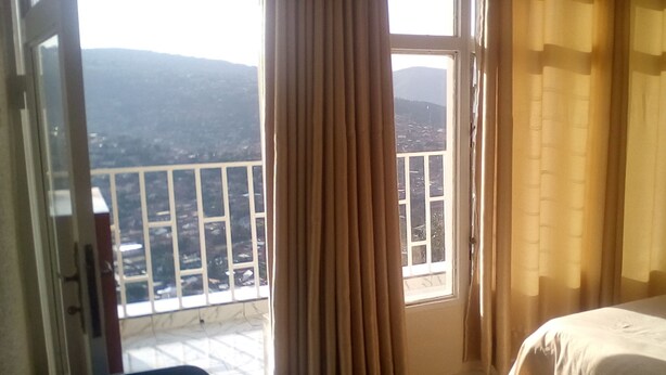 A hotel room with a balcony, a bed, and curtains. - Eminence Hotel (Kigali)