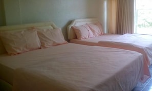 Two beds with white linens in a room with a window and curtains. - Eminence Hotel (Kigali)