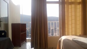 A hotel room with a bed, a wardrobe, and a window with curtains. - Eminence Hotel (Kigali)