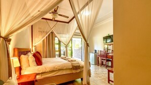 Ein Schlafzimmer mit einem Himmelsbett, einem Schreibtisch und einem Sessel.