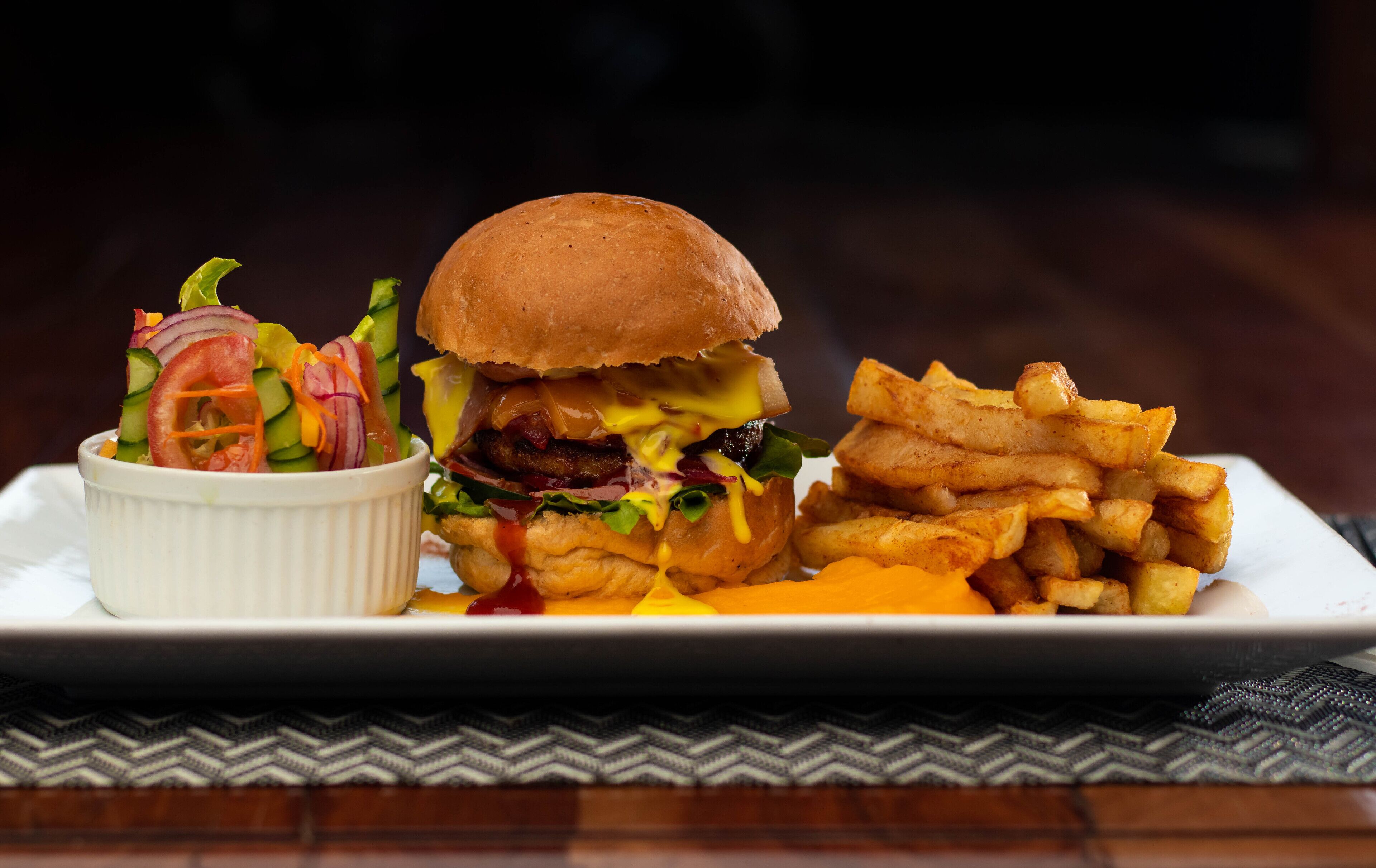 Un piatto con un hamburger, patatine fritte e un'insalata.