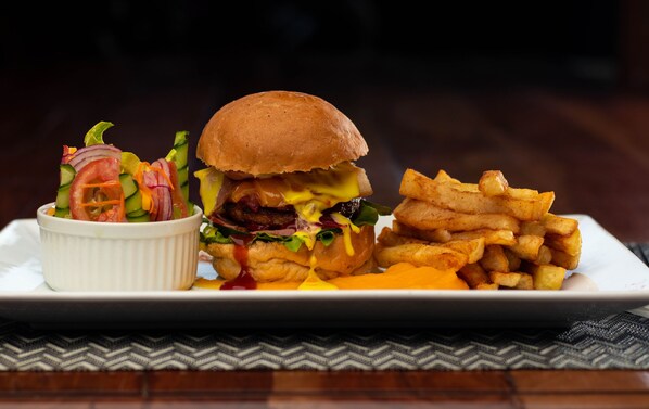 A plate with a burger, fries, and a side salad. - Dzimbahwe Guest Lodge (Victoria Falls)