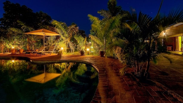 Ein Poolbereich bei Nacht mit einem Weg, Liegestühlen und einem Sonnensegel.