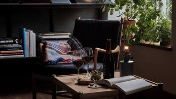 Un rincón acogedor para leer, con un sillón, una mesa y una estantería llena de libros.