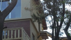 A two-story building with a wooden deck and a staircase leading to an upper level. - Merlión (Mar de Las Pampas)
