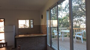 A kitchen with a refrigerator, a sink, and a window overlooking a deck with chairs. - Merlión (Mar de Las Pampas)