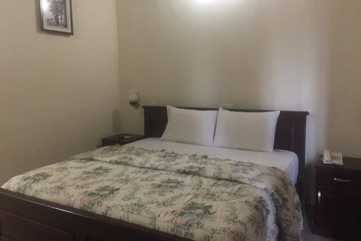 A bedroom with a bed, a nightstand, and a wall-mounted telephone.
