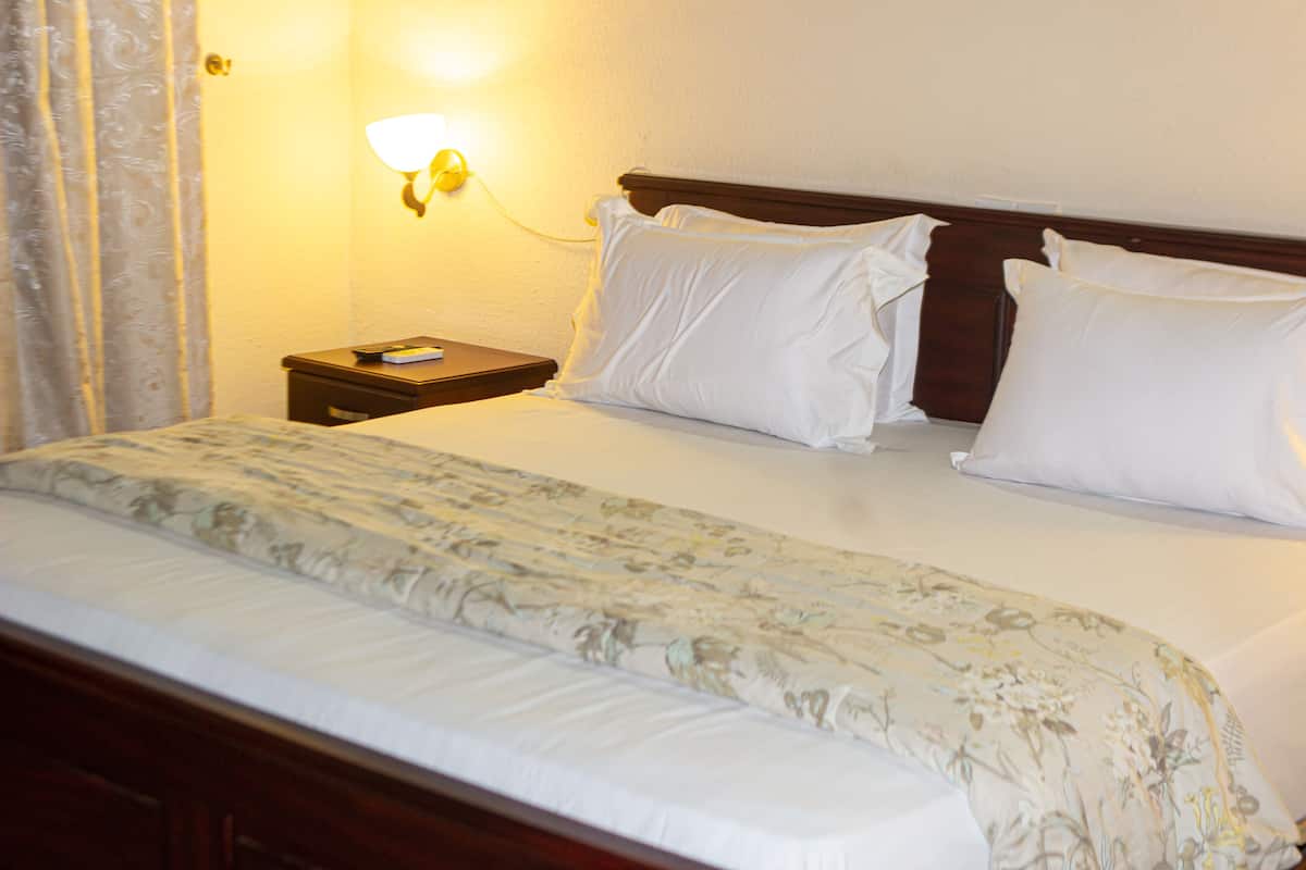 A hotel room with a neatly made bed, a bedside table with a lamp, and a floral bedspread.